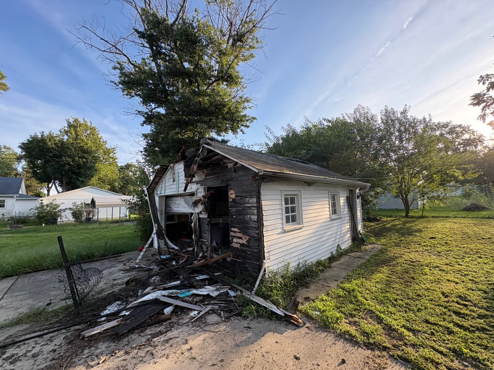 Damaged detached garage before demolition, viewed from the driveway