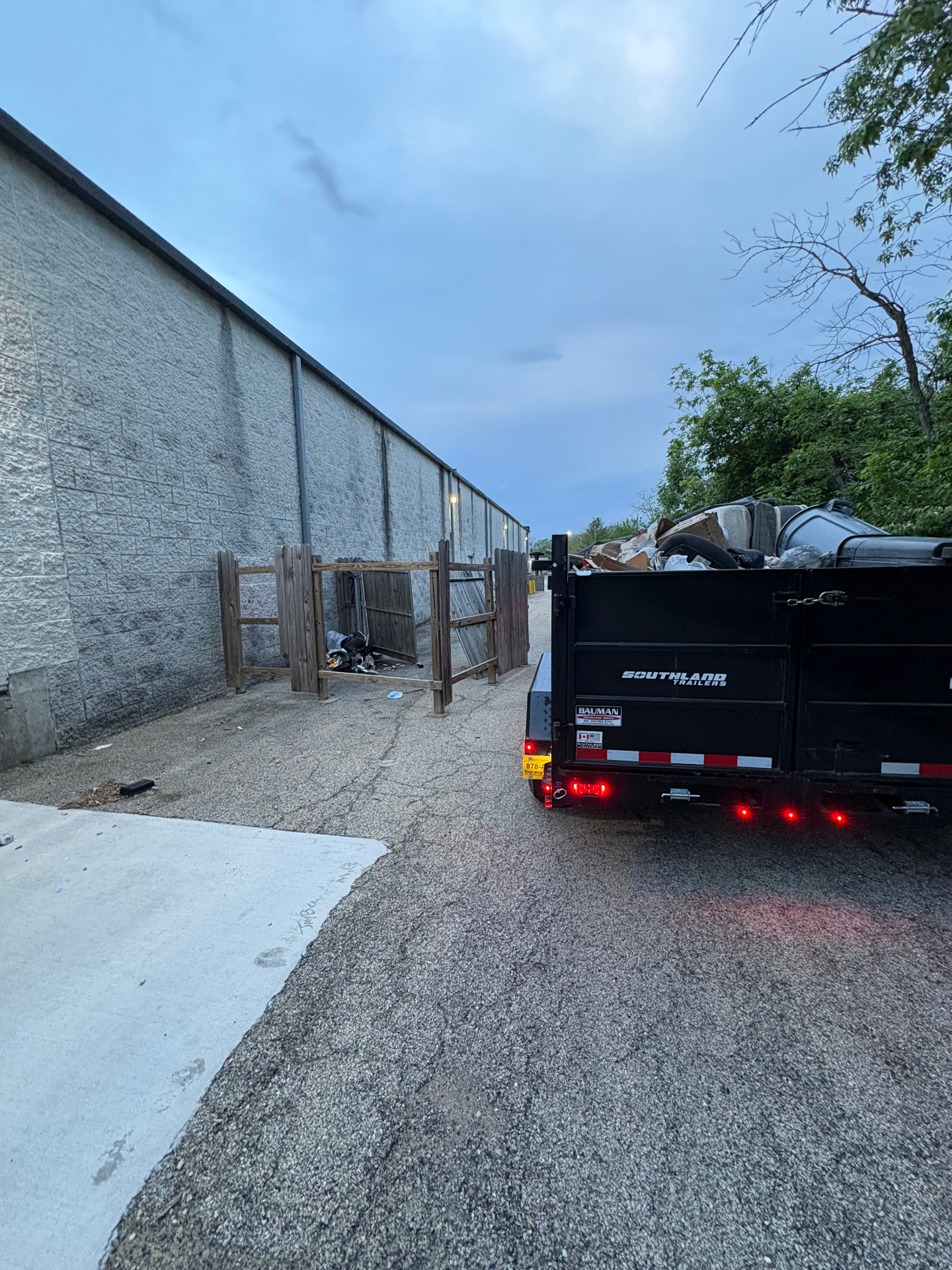 TrashDash dump trailer loaded with debris after an illegal dumping pickup behind a Central Illinois commercial property.